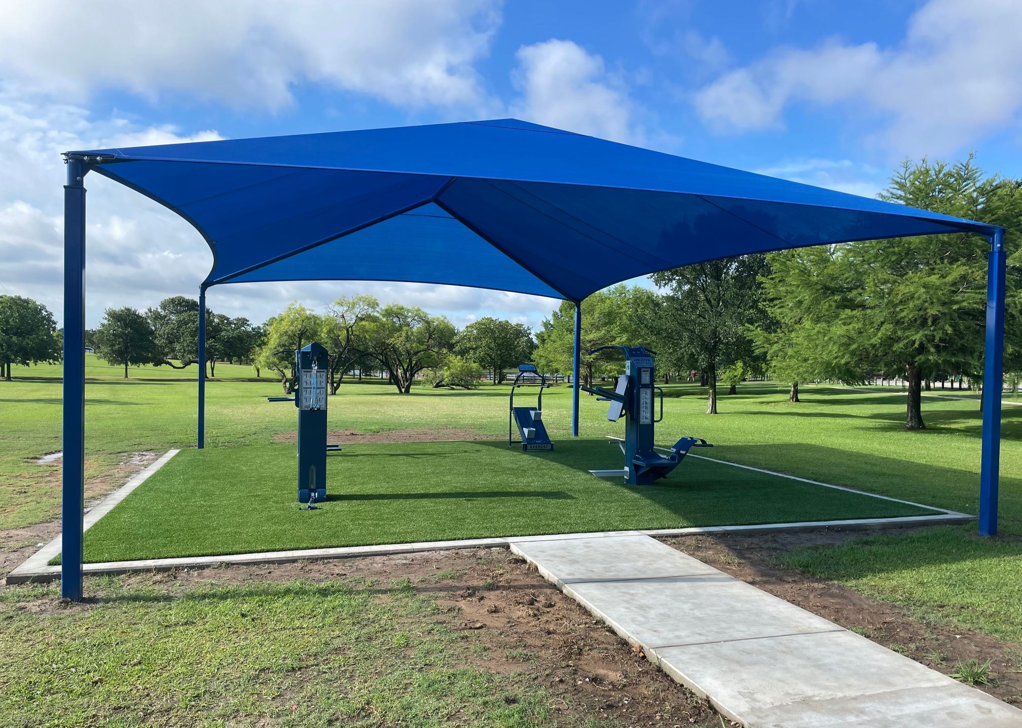 A shade structure over the Outdoor-Fit exercise equipment  in n Chisholm Park, City of Hurst, Texas