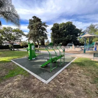 Outdoor fitness equipment installed in a fitness cluster beside a community playground, encouraging family-friendly outdoor exercise.