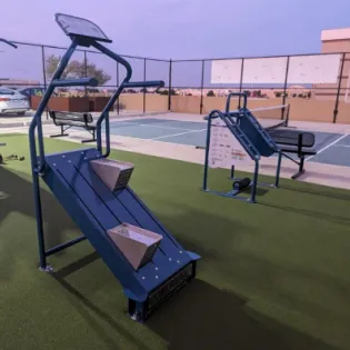 Outdoor fitness equipment installed near a park playground with clear sightlines for supervising parents